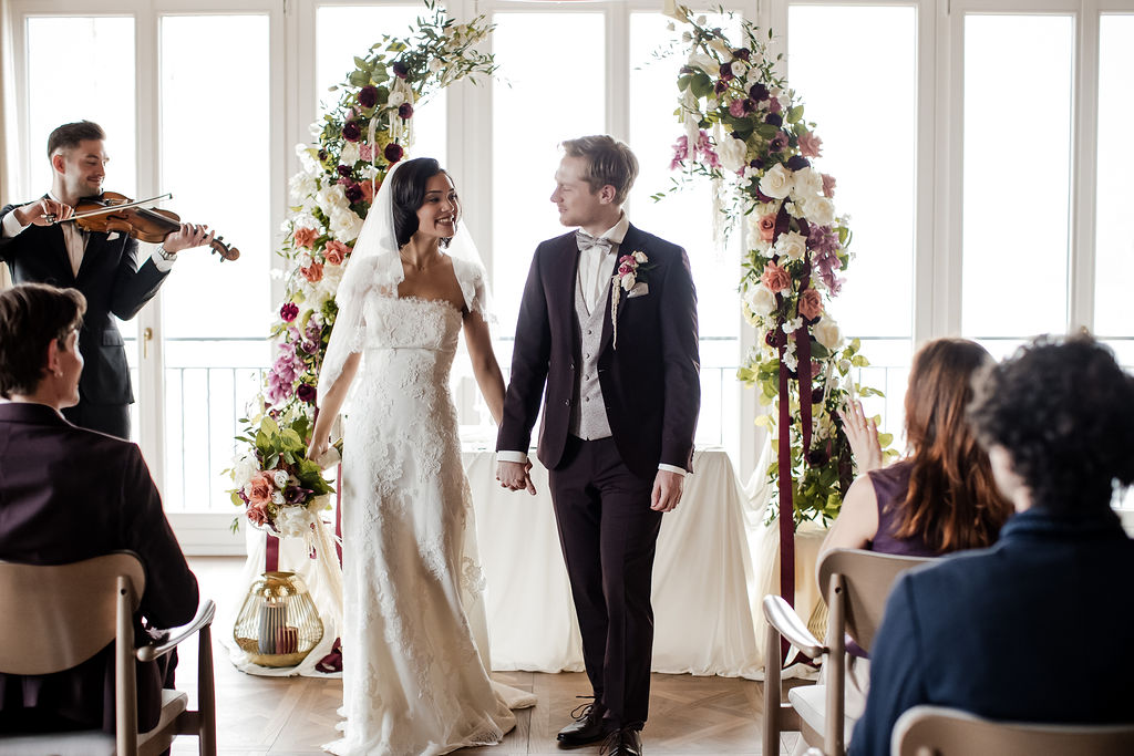 Brautpaar vor dem Traualtar im Glassalon vom Rosewood Schloss Fuschl. Begleitet von Glanz Hochzeiten, Hochzeitsplaner aus München