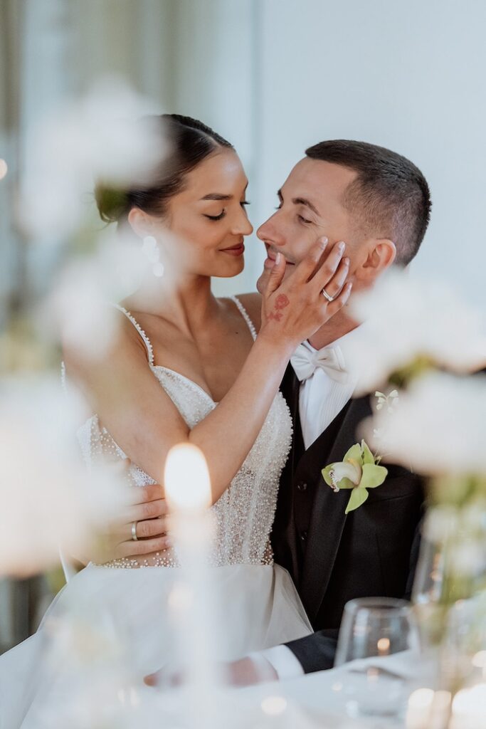 Brautpaar sitzt sich am Tisch in den Armen - Heiraten auf Schloss Dachau begleitet von Glanz Hochzeiten Hochzeitsplaner aus München